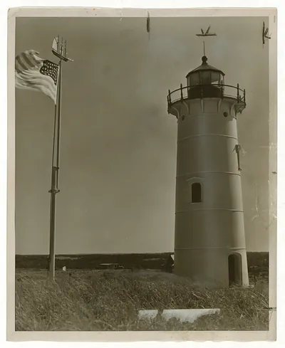 Lighthouse with American flag and weathervane, sepia photograph