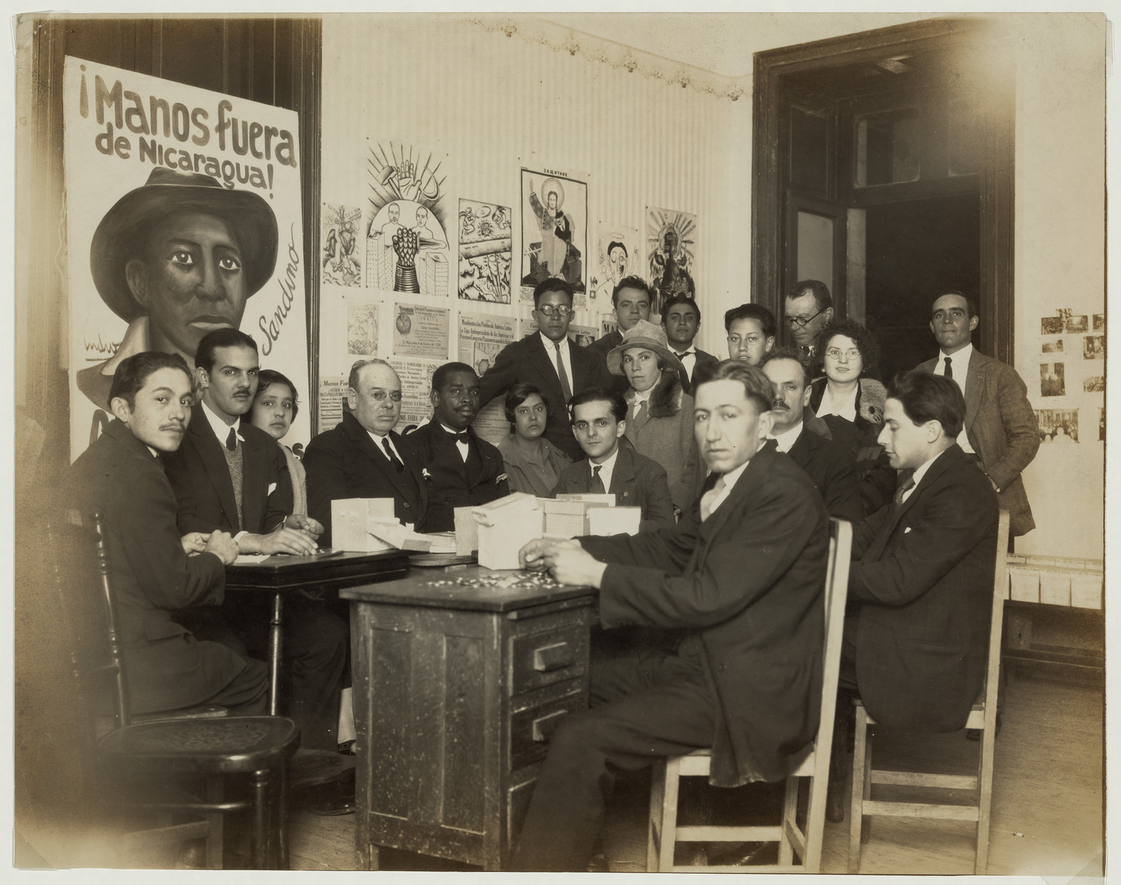 Group of men and women before a "Manos fuera de Nicaragua" poster — vintage poster