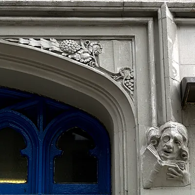 Stone mascaron of a monocled reader with a book