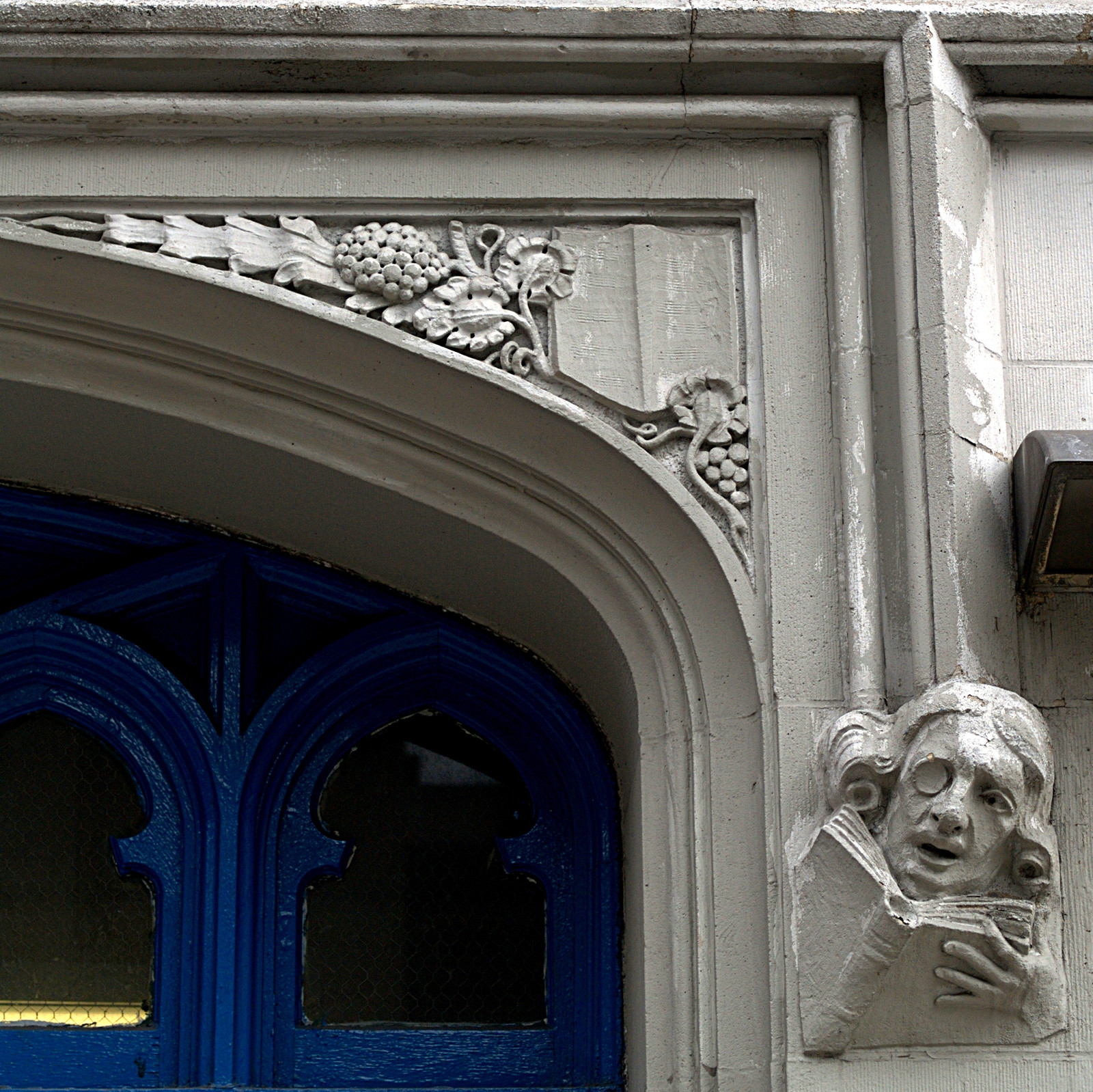 Stone mascaron of a monocled reader with a book — historic image