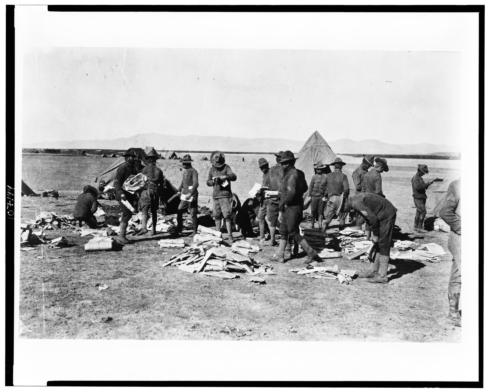 [Army camp looking at mail delivery], [1915(?)] — historic photograph