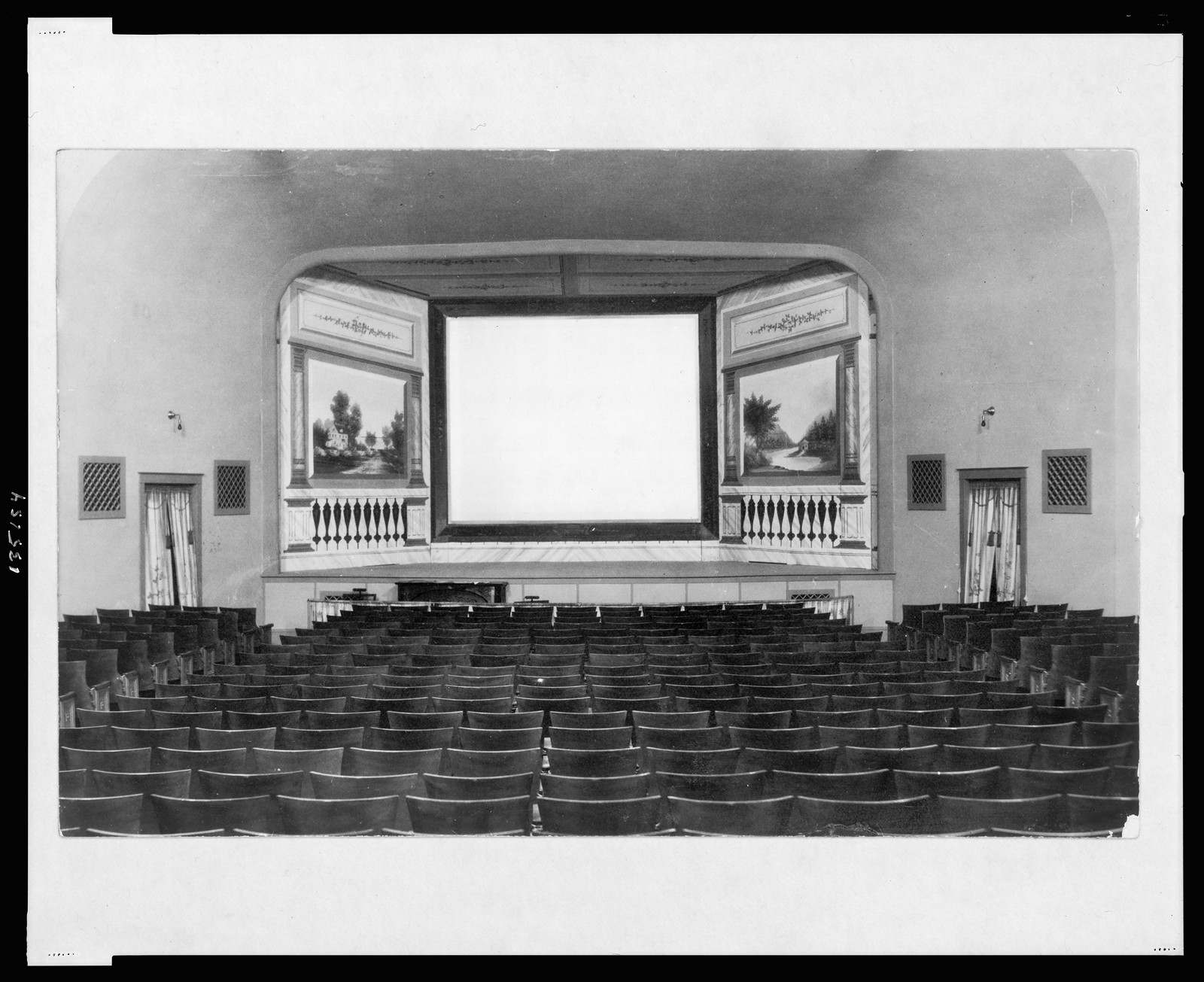 Interior of a movie theater with blank screen and seats — historic image