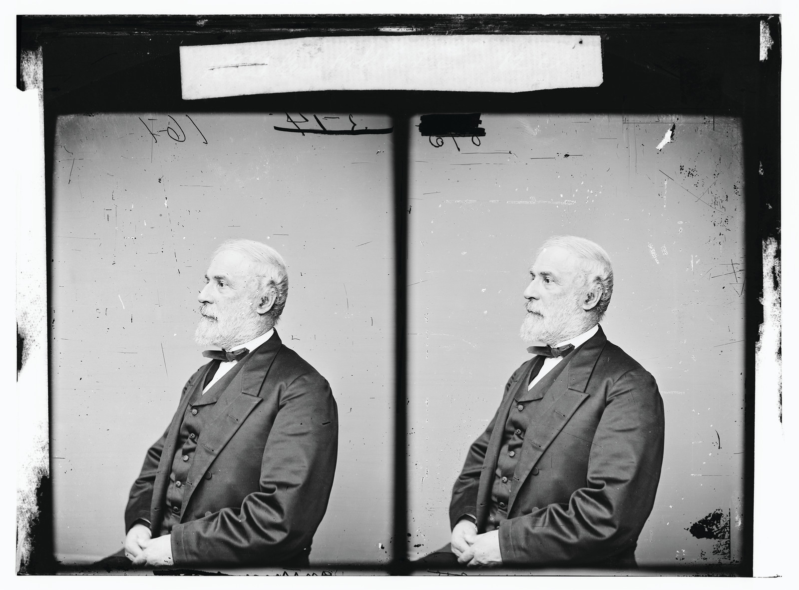 Bearded man in dark suit and bow tie, seated in profile — historic image
