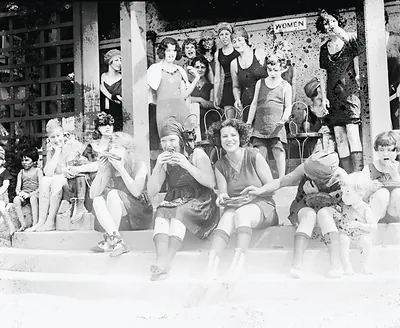 Women in bathing suits eating on beach steps