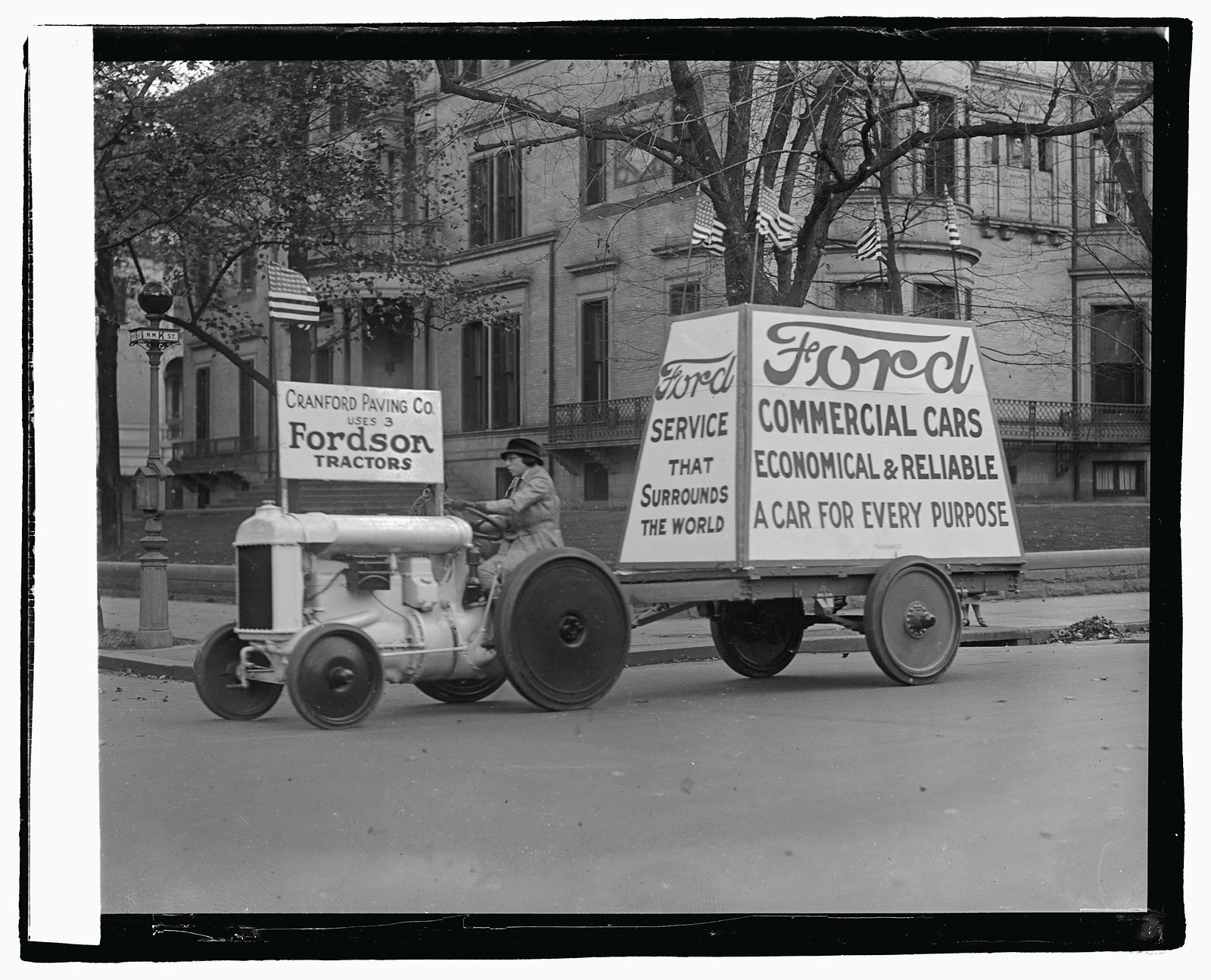 Fordson tractor pulling Ford Commercial Cars advertising trailer — historic image
