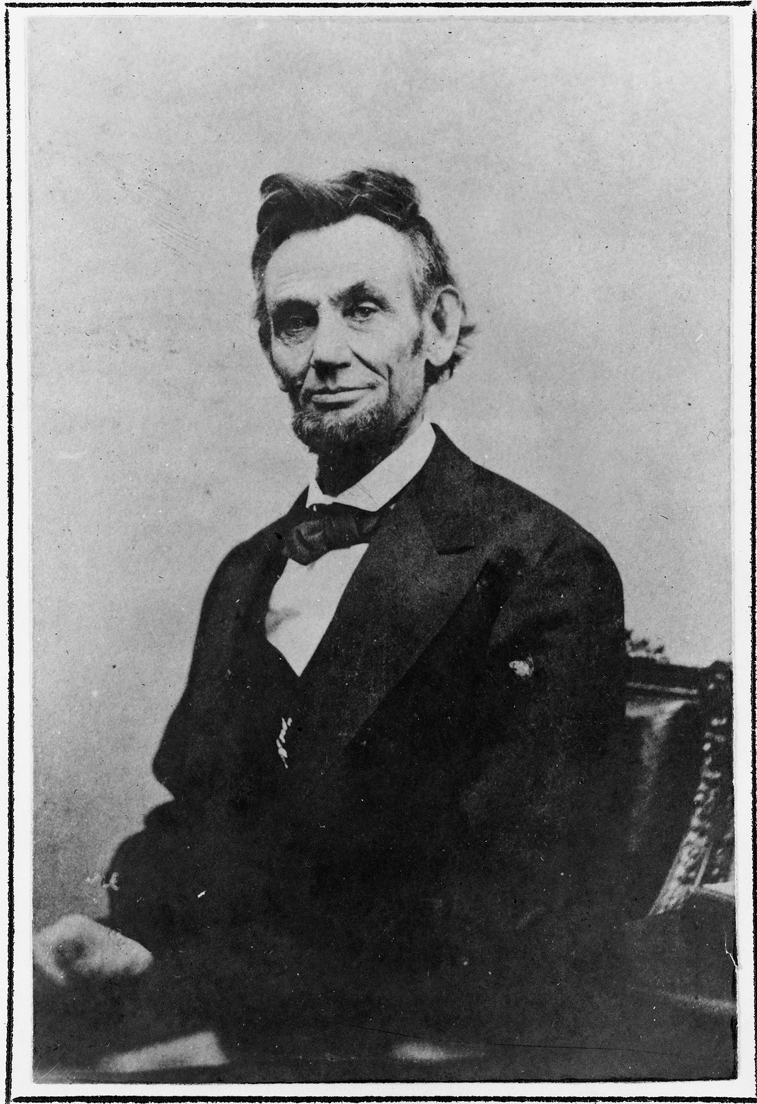 Seated man in dark suit and bow tie, black and white portrait photograph — historic photograph