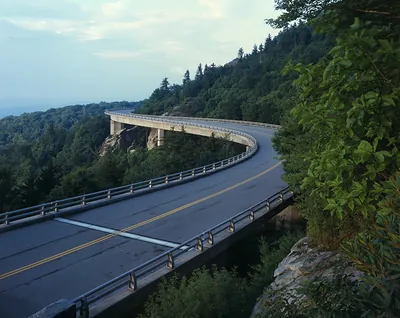 Curved concrete viaduct winding through forested mountain slopes