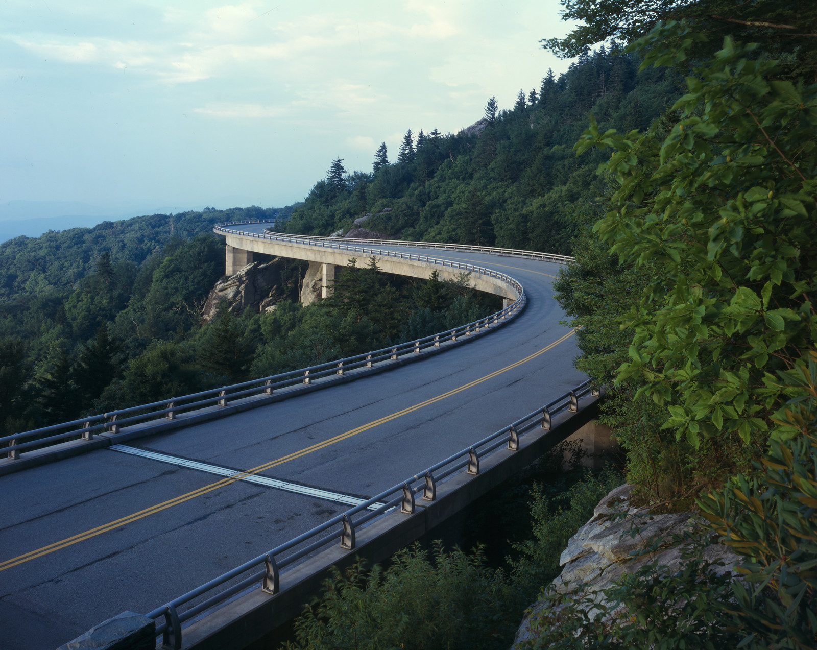 Curved concrete viaduct winding through forested mountain slopes — historic image