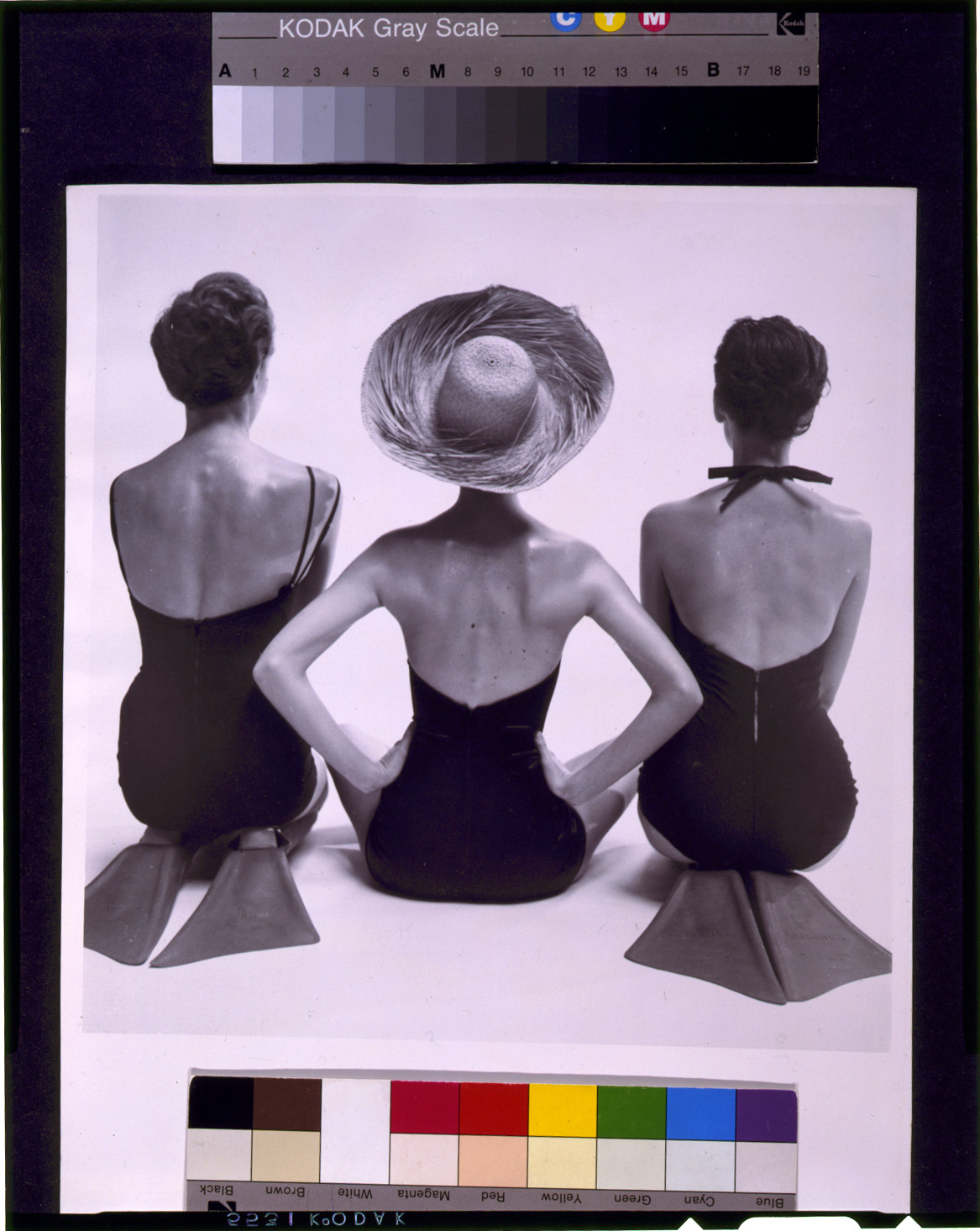 [Back view of fashion models in swim suits, two kneeling wearing swim fins, and one seated], [1950] — historic photograph