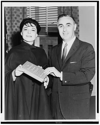 [Anne Bancroft, three-quarter length portrait, standing, facing front, holding book, with Abraham Ribicoff, at kick off for American Hearing Society's 33rd annual educational campaign]