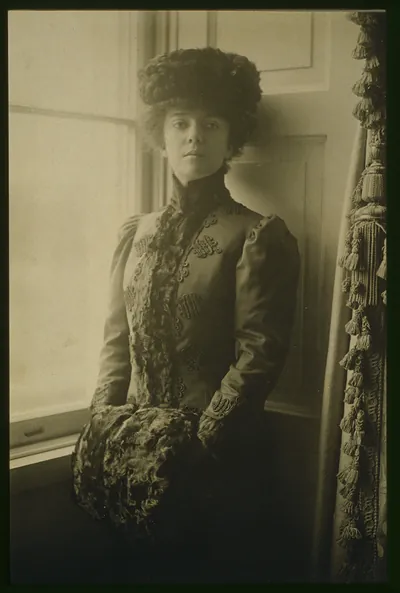 [Alice Roosevelt Longworth, three-quarter length portrait, wearing hat and muff, standing at window, facing front]