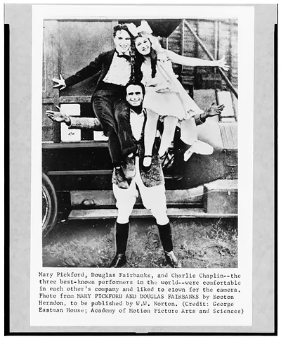 [Mary Pickford and Charlie Chaplin seated on shoulders of Douglas Fairbanks]