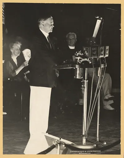 Speaker at NBC and Columbia radio microphones, with seated audience