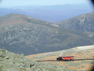 Red cog railway train climbing a barren mountainside