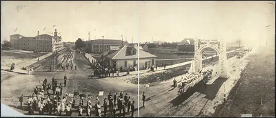 Panoramic photograph of parade passing a Welcome Home arch