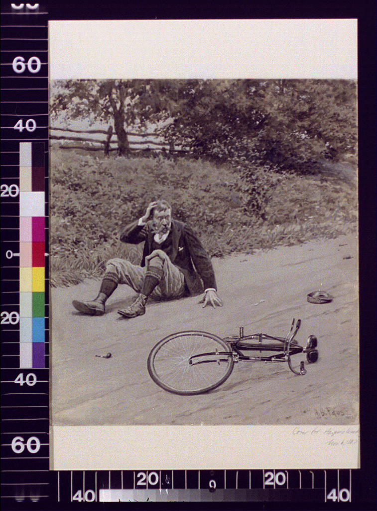 Man sprawled on road beside overturned bicycle — historic image