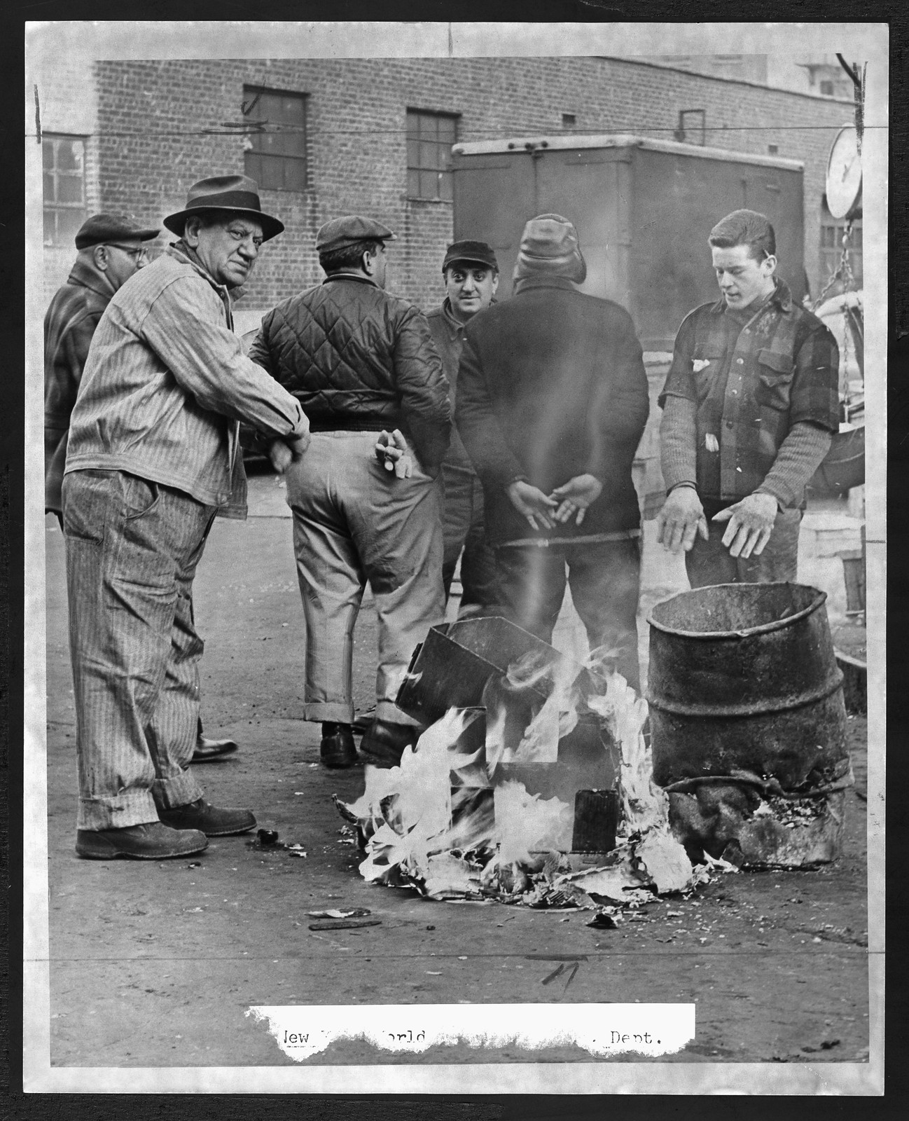 Men Burning Papers in Yard Beside Metal Barrel — historic image