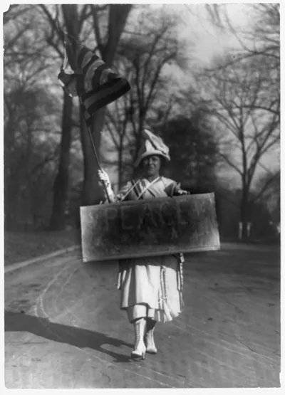 [Woman marching with peace sign and U.S. flag, disarmament conference, Washington, D.C.]