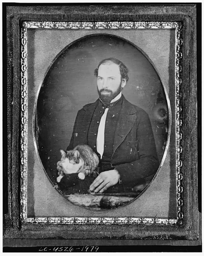 [Unidentified man with cat, three-quarter length portrait, full face, seated]
