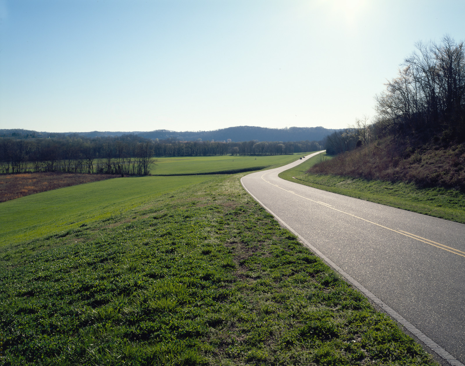 Curving two-lane road through green fields and hills — historic image