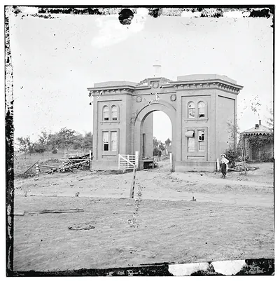 Brick arched cemetery gatehouse with a figure at right