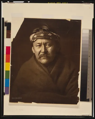 [A Navajo man, head-and-shoulders portrait, wearing blanket and headband, facing front]
