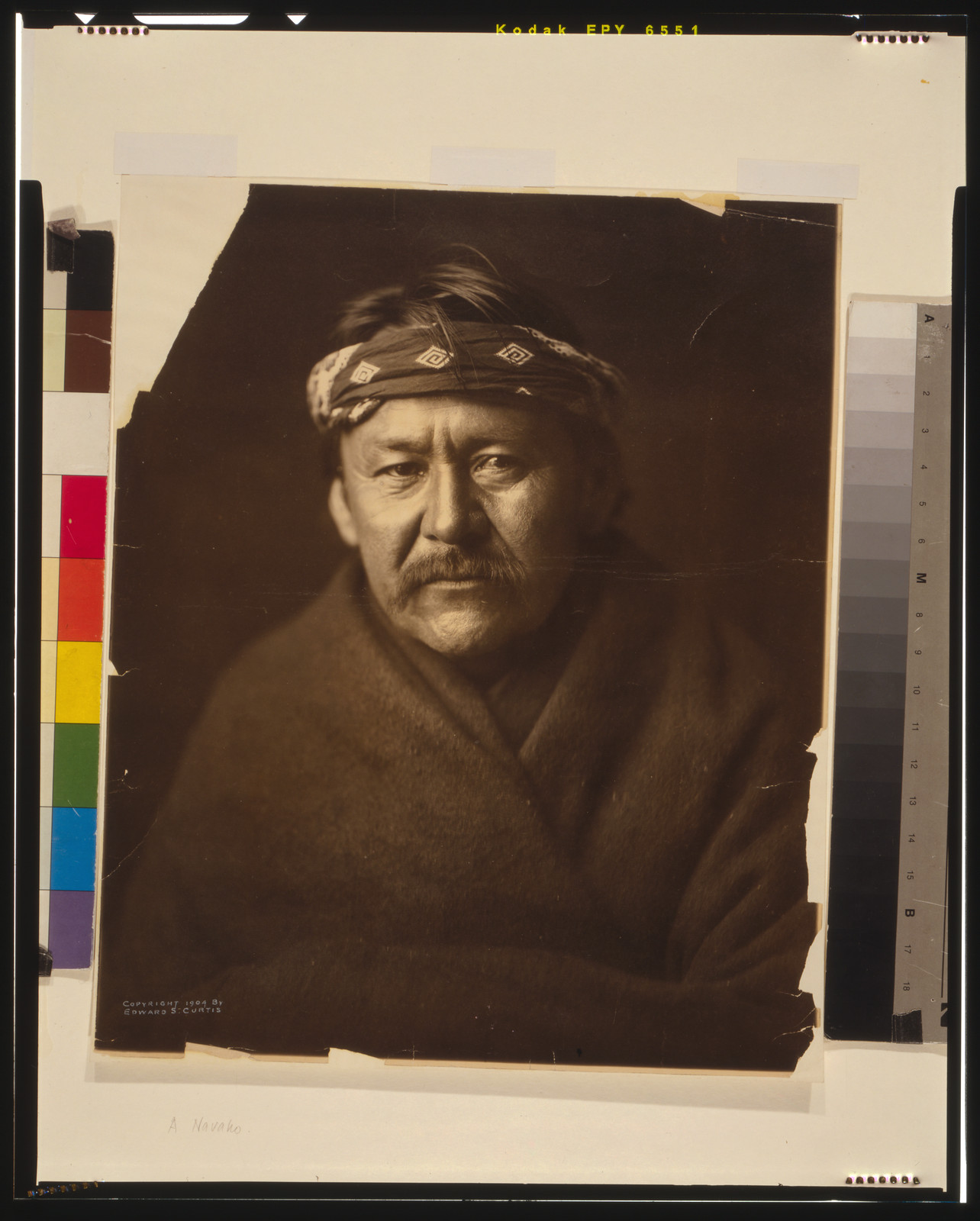 [A Navajo man, head-and-shoulders portrait, wearing blanket and headband, facing front], c1904. — historic photograph
