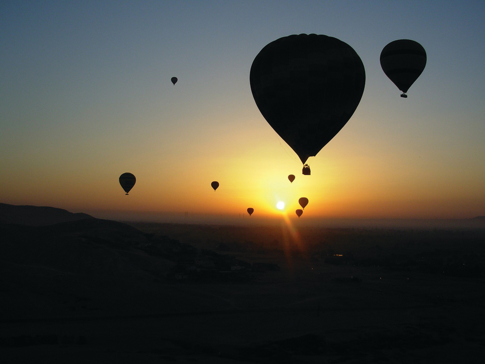 Hot air balloons silhouetted against a sunrise sky — historic image