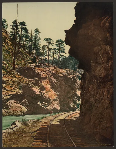 Railway curving through a rocky canyon beside a green river