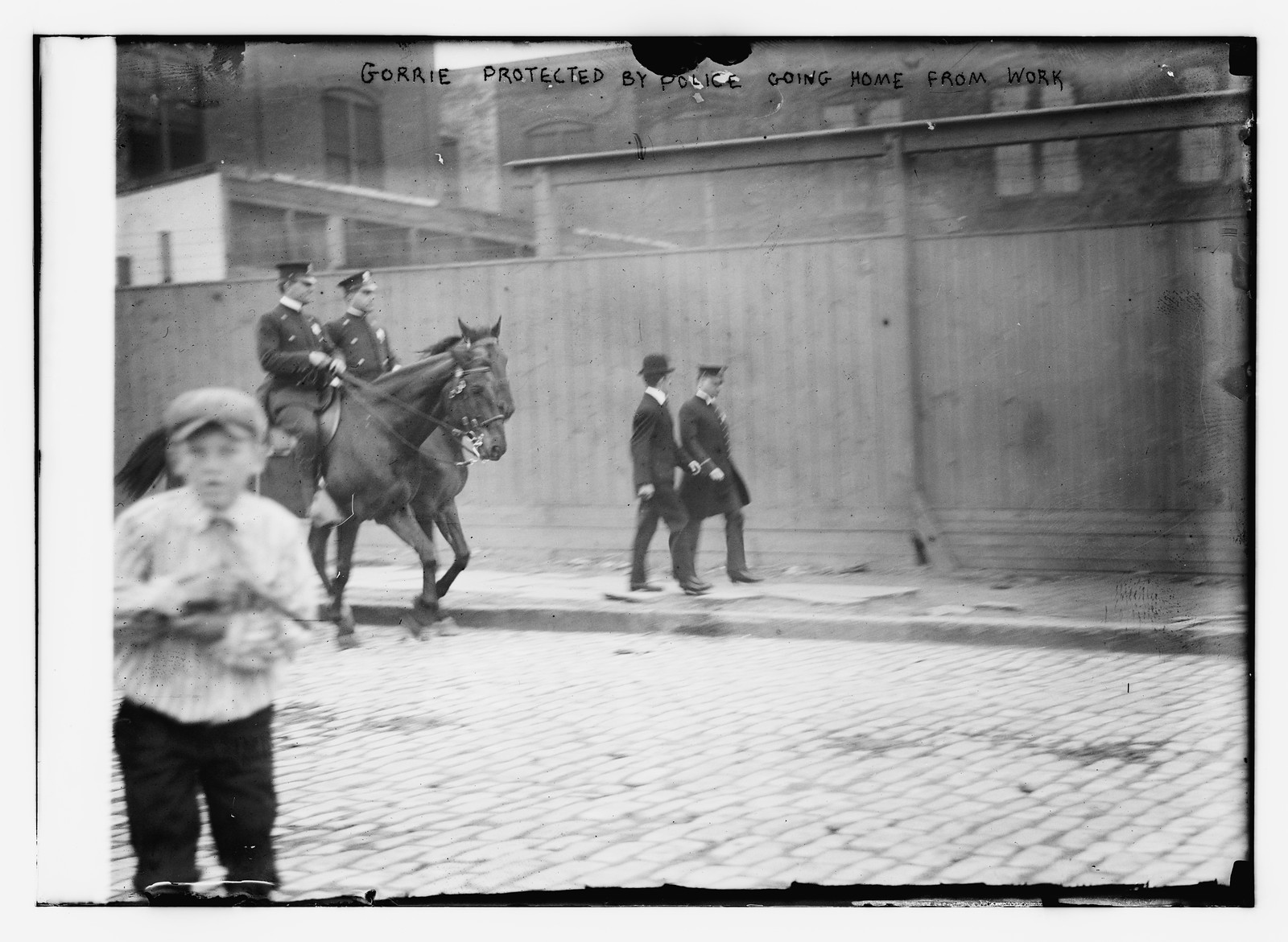 Gorrie protected by police going home from work, n/a — historic photograph