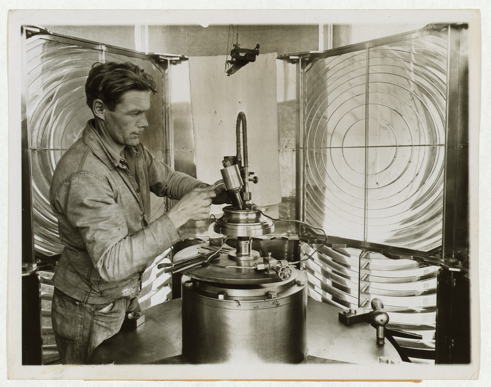 Man servicing a lighthouse lens apparatus — historic image