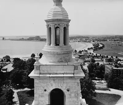 Marble monument tower top with lantern over harbor