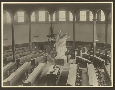 Sepia photograph of lecture hall interior with white statue