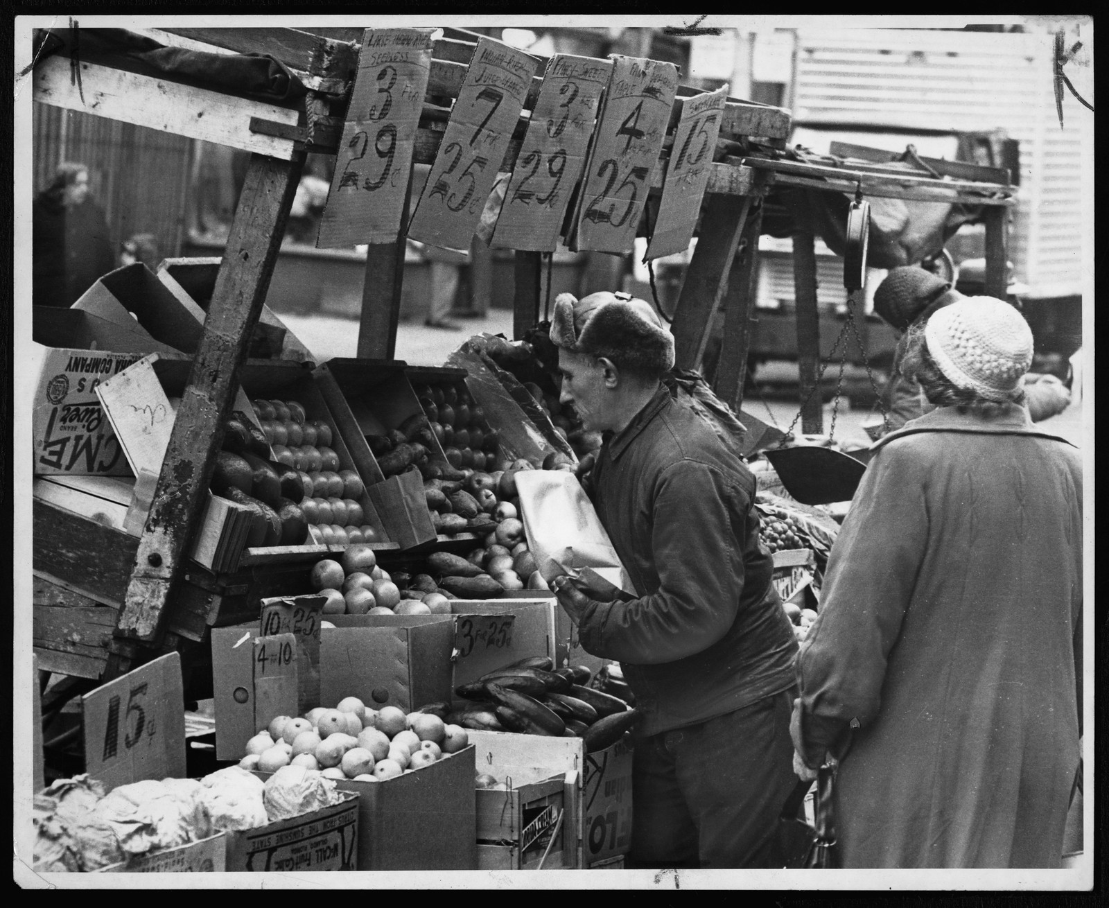 Market vendor selling apples and produce from a stall — historic image