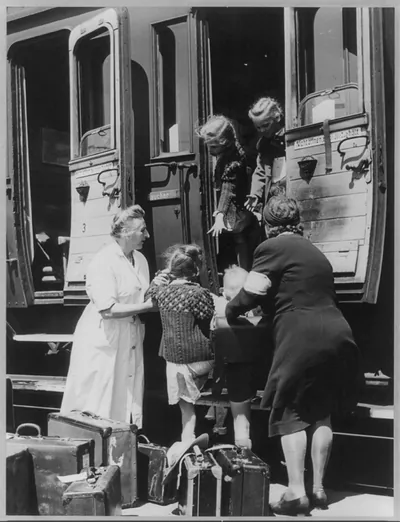 [Two women helping children board train]