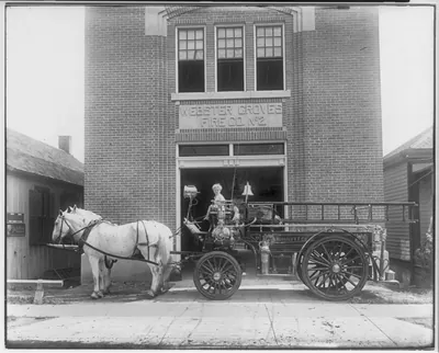 [Horse-drawn fire truck in front of Webster Groves Fire Co. No. 2; small boy in drivers seat, St. Louis, Missouri]