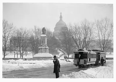 Snow-covered Capitol dome with streetcar and monument, winter photograph