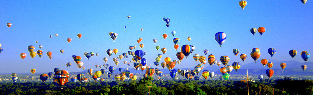 Hot air balloons rising over a valley with mountains — historic image