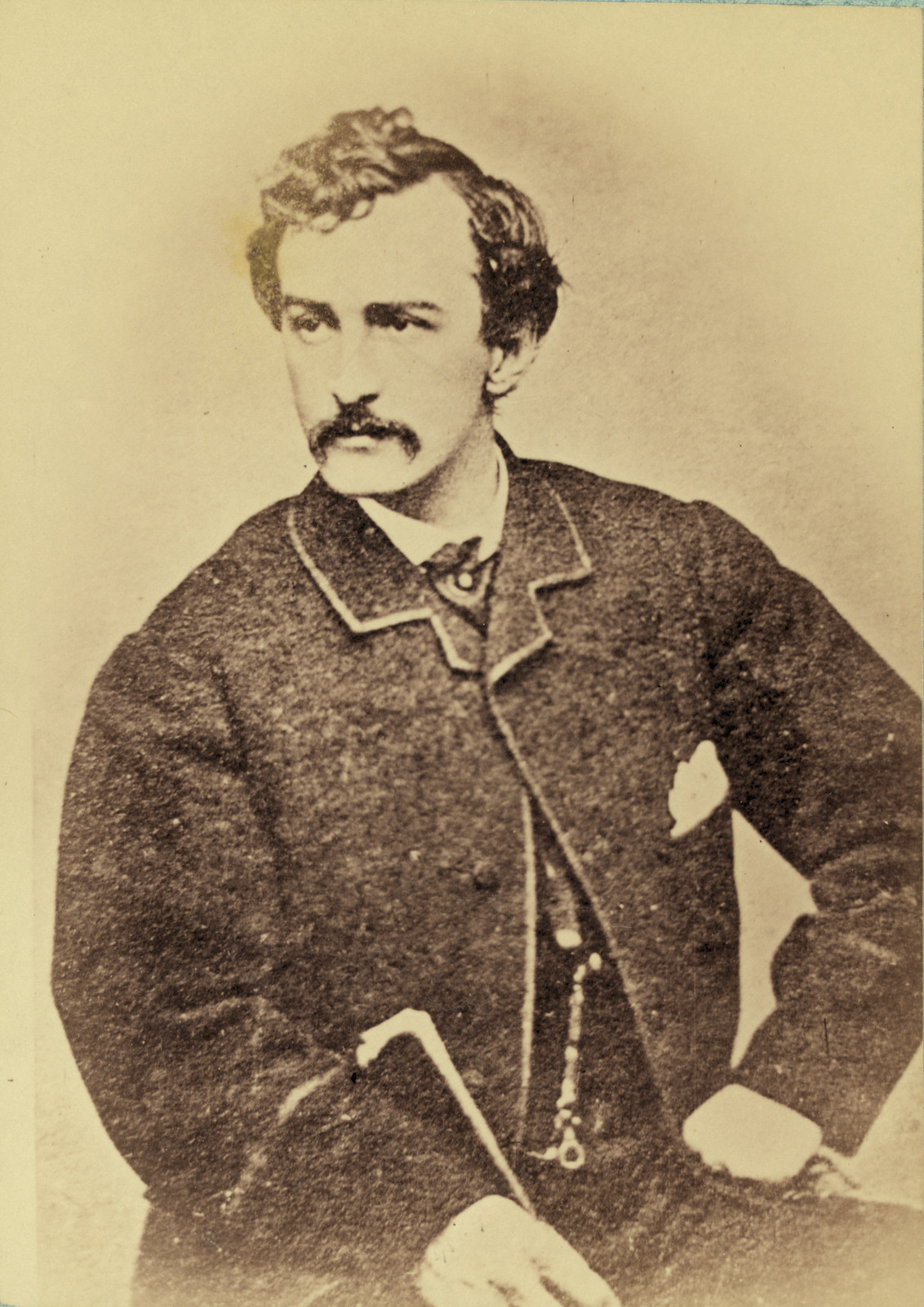 Sepia portrait of a moustached man in frock coat with cane — historic image