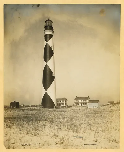 Cape Lookout lighthouse with black and white diamond pattern, hand-colored photograph