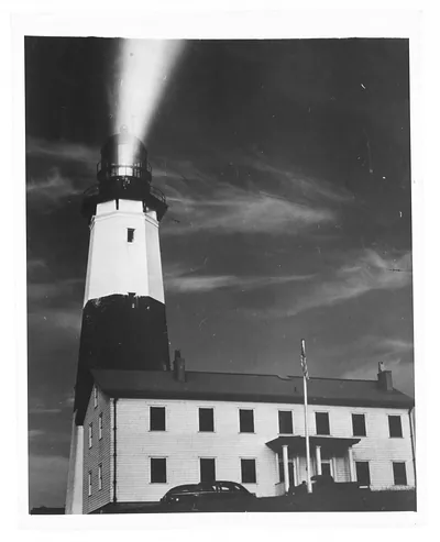 Lighthouse beam over a keeper's residence with flagpole
