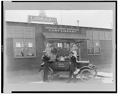 [Three men at automobile in front of American Library Association, Camp Cody library]