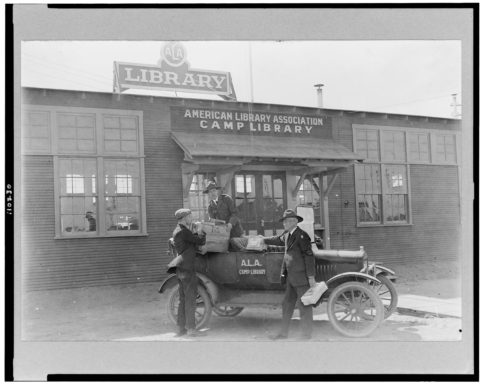 [Three men at automobile in front of American Library Association, Camp Cody library], [1918 or 1919] — historic photograph