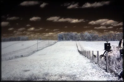 Infrared photograph of a field, fence and farm machinery