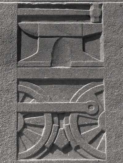 Relief carving of an anvil and locomotive wheels with coupling rod