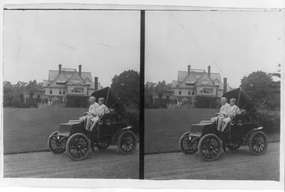 Thomas A. Edison and son(?) in automobile and large house in background