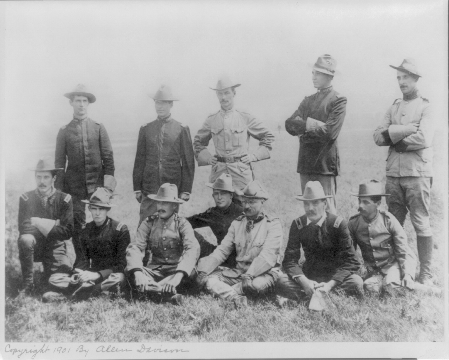 [Theodore Roosevelt, full, in uniform, sitting cross-legged on ground, with Army officers], 1901 — historic photograph