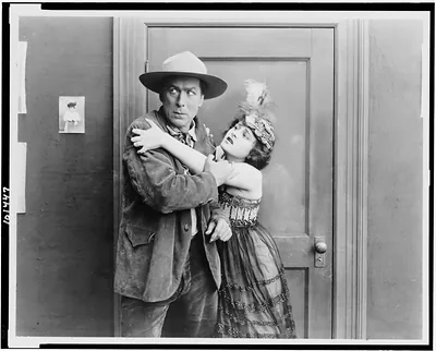 [Motion picture still from The Narrow Trail, showing William S. Hart, as outlaw Lee Harding, trying to escape from dance hall queen, who is clinging to him]