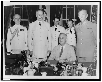 [President Roosevelt seated at desk in White House with group standing around him: General Henri Honore Giraud, commander of French forces in Africa (left); Admiral William Leahy (far left); General George C. Marshall (right); and two of Giraud's aides (back)]