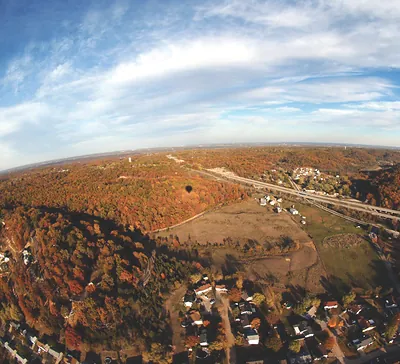 Aerial view of autumn forest, highway and houses